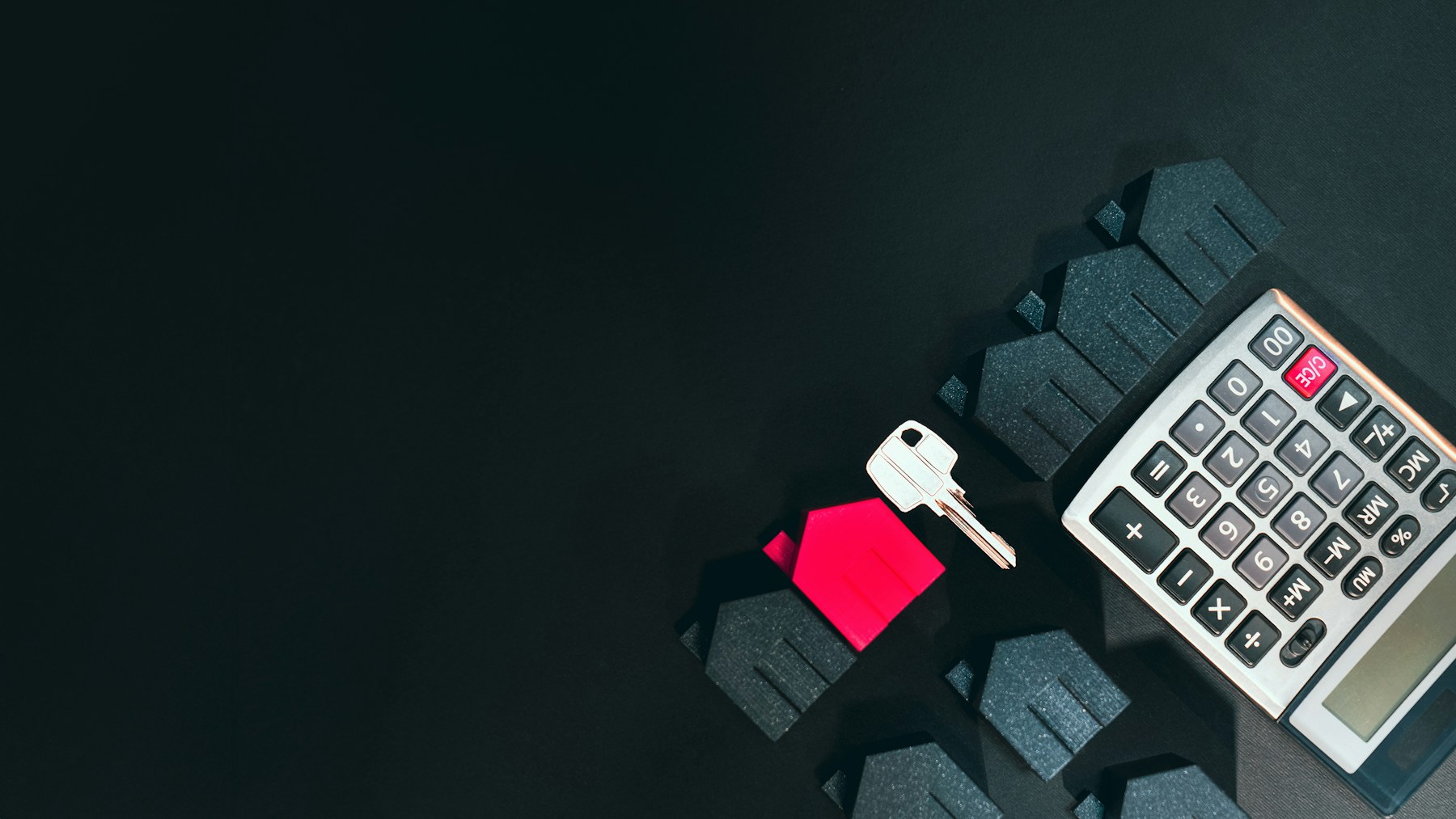 House key, home model and calculator representing real estate finance